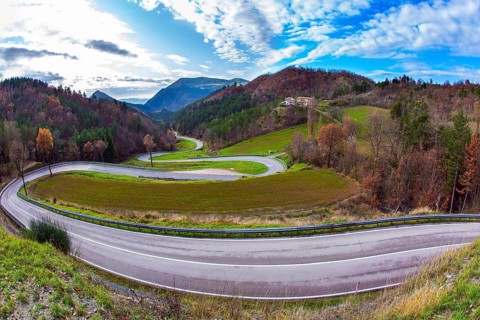 Wet asphalt. Cloudy winter day. The picturesque mountain slopes are covered with coniferous forest.