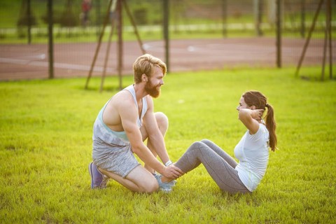 Sit ups fitness couple exercising sit up outside in graß Fit people working out cross training.
