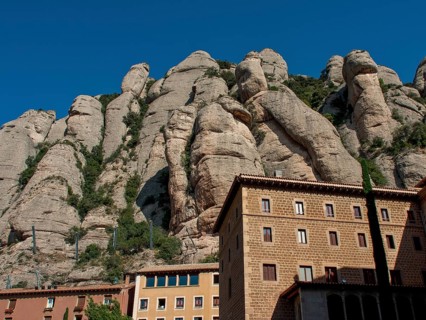 Building at the foot of rocky mountains under a clear sky in Montserrat, montserrat, spain