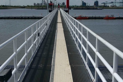 Metal walkway over the water, flanked by boats and an industrial backdrop, lillo, antwerp, belgium
