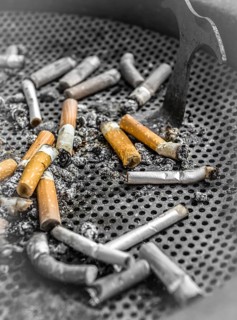 Smoked cigarettes butts in a dirty ashtray. Unhealthy life concept