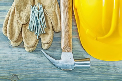 Hard hat protective gloves claw hammer nails on wooden board construction concept