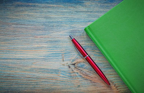 Green notepad pen on vintage wood board copy space education concept