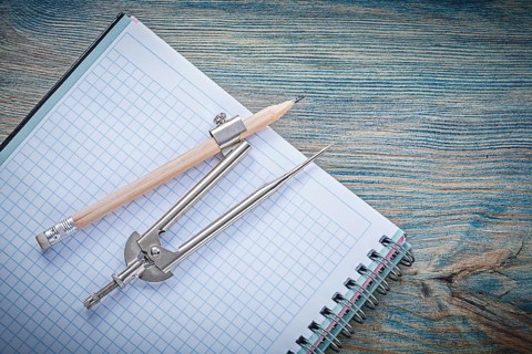 Vintage pair of compasses pencil open blank copybook on wooden board construction concept