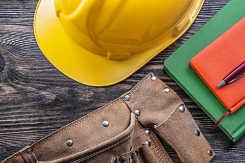 Tool belt note-books pen building helmet on wooden board construction concept