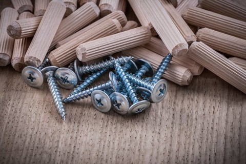 Woodworking dowels and construction nails on wood board top view