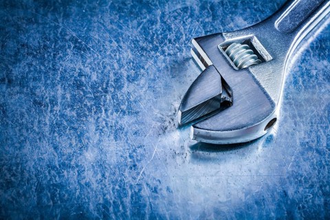 Copy space of stainless adjustable wrench on scratched metallic background construction concept