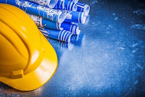 Blue construction drawings yellow hard hat on scratched metallic background