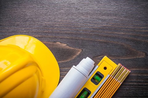 Horizontal view of blueprint roll construction level building helmet and wooden meter on vintage