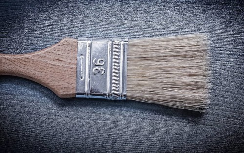 Paintbrush on wooden board close up view construction concept