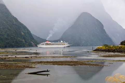 Cruise ship in the evening of an overcast day in the majestic Milford Sound on the South Island of