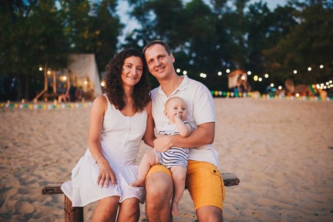 Theme of family summer holidays on the beach. Caucasian man and woman dad and mom hug a small baby