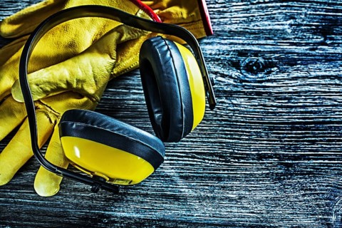 Safety earmuffs leather gloves on wooden board