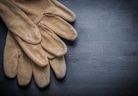 Two working leather gloves on dark wood board