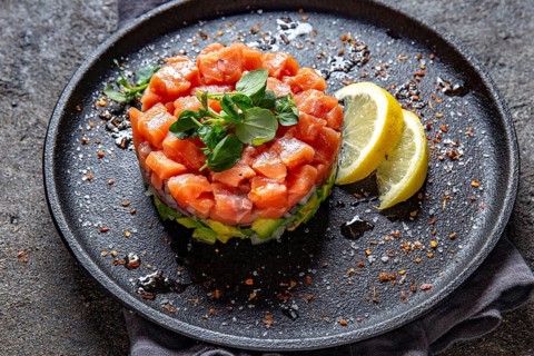Food, Raw salmon, avocado purple onion salad served in culinary ring on black plate. Black concrete