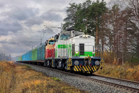 VR freight train with two diesel locomotives and carriages full of wood logs on the move on a day