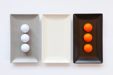 Different ceramic dishes with golf balls on over white background, rectangle dish