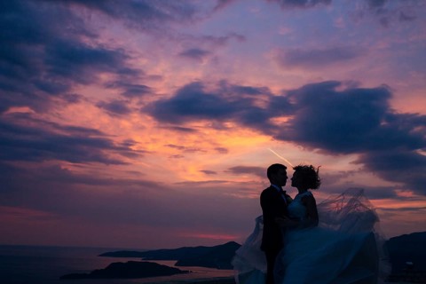 Silhouette of the newlyweds against the sky at sunset. Wedding in Montenegro. Silhouette of a