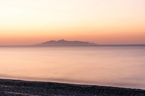 Dawn at sunrise, view from the lava beach near Kamari to the island of Anafi, long exposure, island