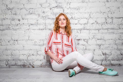 Young beautiful caucasian woman student is sitting on the floor near a white brick wall. Girl with