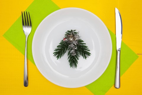 White plate and green Christmas decoration on the yellow wooden table.Top view.Flat Lay Image