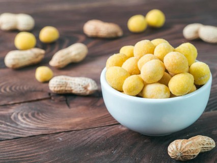 Peanut snack for beer, wine, party bar. Salted peanuts in yellow cheese glaze on brown wooden table