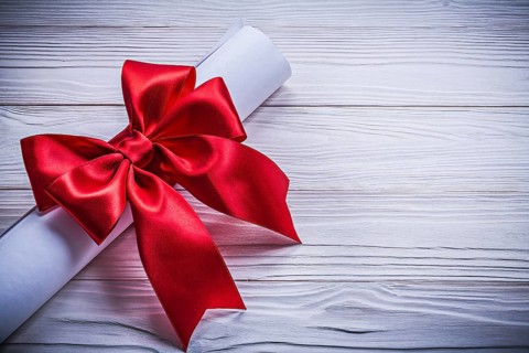 Roll of paper with red bow on wooden board holidays concept