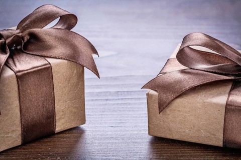 Two vintage pepr giftboxes with brown bows on old wooden board very close up view holiday concept