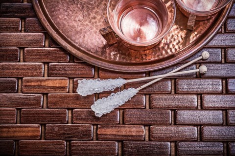 Horizontal view of coppery tray tea cups sugar sticks