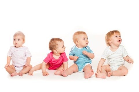Group of witty babies sitting in different clothes, isolated on white background