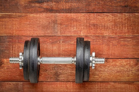 Heavy iron dumbbell on a rustic wood background - fitness concept