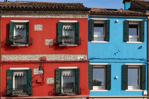 Close-up of red and blue houses with classic shutters and rustic façade, Burano, Venice, Veneto