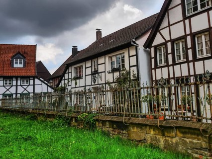 Large half-timbered houses with a fenced garden and clouds in the sky, Herten, North