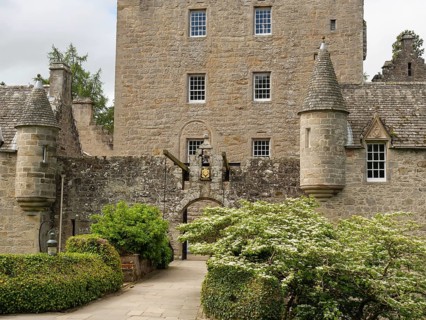 An old castle with stone walls, towers and an entrance surrounded by green plants, inverness,