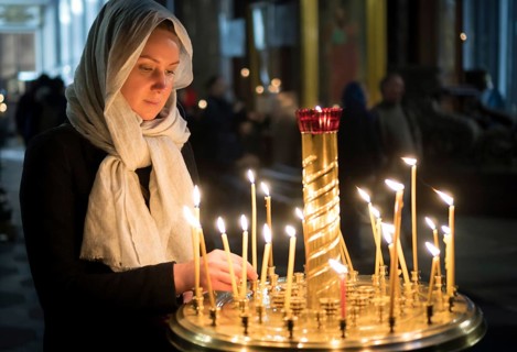 Woman lights the candle in russian orthodox church