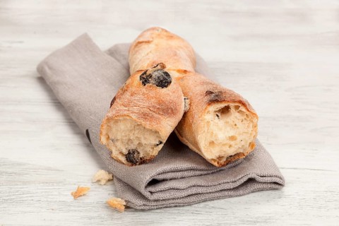 Delicious pastry on wooden table. Olive baguette