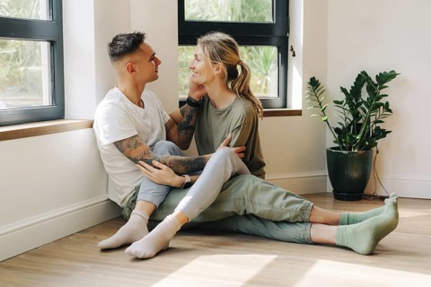 Junges, glückliches Paar in ihrer neuen Wohnung, das sich umarmt, während es bei einem Date auf dem