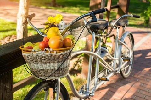 Basket of fruits on bicycle. Bike and bouquet on fence. Organize a picnic for two. Warm days of