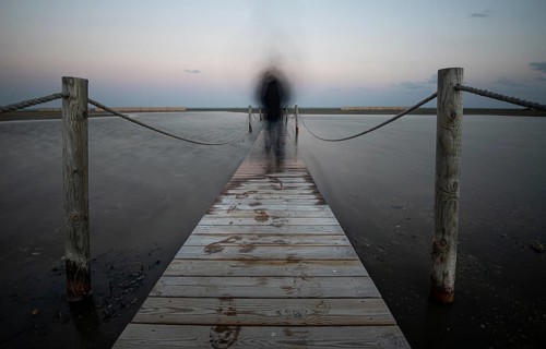 An unrecognised person walking like a ghost at a wooden pier