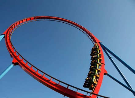 People on a dangerous Rollercoaster Ride in an amusement park against a blue sky