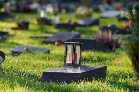 Grave lantern on a gravestone of a cemetery with graves of the poor in front of a blurred