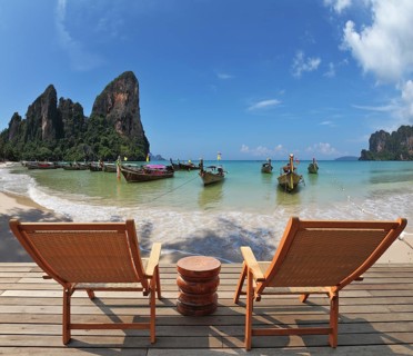 Cozy beach rest. Two wooden chaise lounges and small bedside table on a wooden scaffold. Native