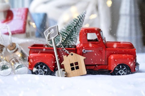 Red retro car with a Christmas tree decorates with the house key in the pickup truck for Christmas.