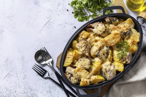 Baked mackerel with potatoes and cheese on a marble tabletop. Top view flat lay background. Copy