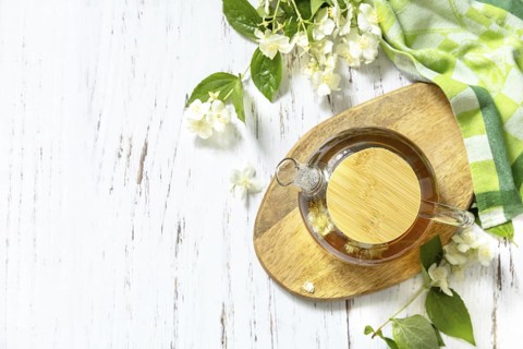 Therapeutic herbal tea. Hot Jasmine tea with jasmine flowers in a glass teapot on a rustic wooden