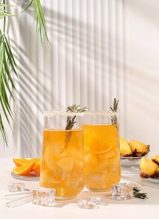 Cold homemade cocktail or lemonade with rosemary, orange, ice and pineapple on a sunny table, Detox