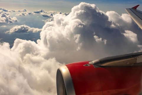 A colour landscape image looking out through airplane window showing land, cloud and sky
