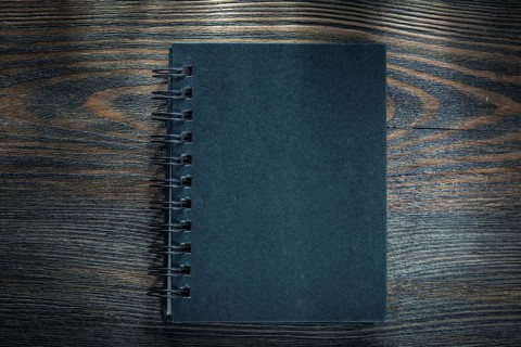 Black spiral notebook on vintage wooden board