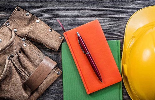 Set of tool belt note-books pen hard hat on wooden board construction concept