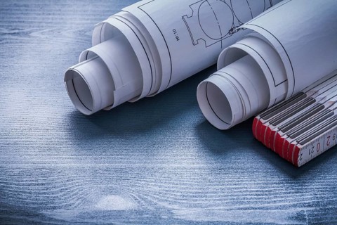 Two rolls of blueprints and white wooden meter
